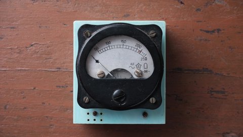 Old analog voltmeter with a metal arrow. The voltmeter arrow moves randomly.