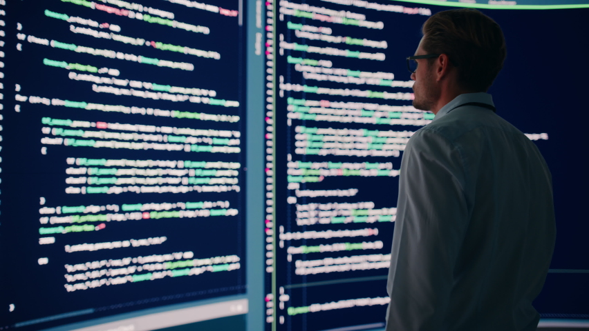 Innovative Startup Concept: Thoughtful Software Engineer Finding Solution, Planning Strategy, Standing and Doing Data Analysis on Big Wall Screen. Programmer Developing e-Commerce App. Back View | Shutterstock HD Video #1078602038
