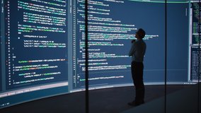 High-Tech Startup Concept: Innovative Male Software Engineer Standing, Doing Big Data Analysis on Wall Screen Showing Porgramming Code. Developing Futuristic e-Commerce App with Machine Learning. Full - Powered by Shutterstock - Get 15% off with code: PIKWIZARD15