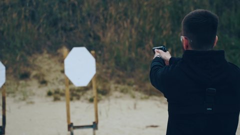Shooting a pistol at a target on the street in a shooting club, a view from behind
