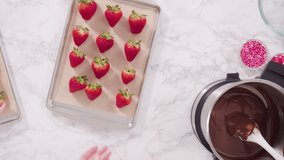 Time lapse. Flat lay. Step by step. Dipping organic strawberries into melted milk chocolate.