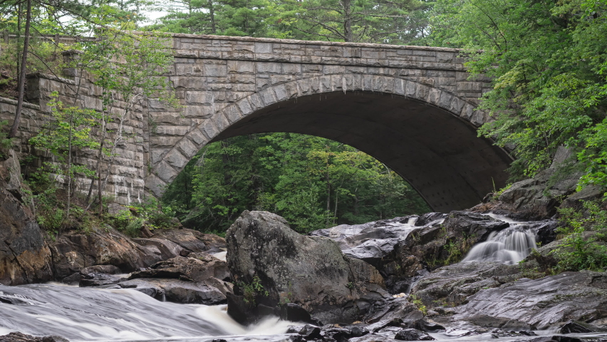 A time-lapse of a stream with a bridge in the background.