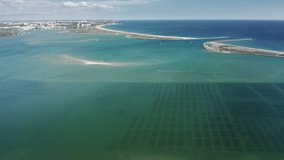 Aerial view of large oyster farm fields under Atlantic water bay near Lagos in Portugal. 4K footage of agriculture business in Europe. Drone shot of sportsmen gliding on kiteboards