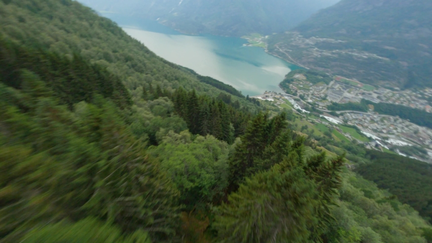 Aerial flight downhill the green mountains towards tourist town Odda and Fjord in Norway - FPV Dynamic drone shot | Shutterstock HD Video #1078617932