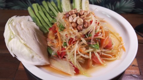 Authentic Thai Cuisine, Somtam, papaya salad with Sweet and Sour Sauce Freshly Made on a White Spinning Plate Close Up