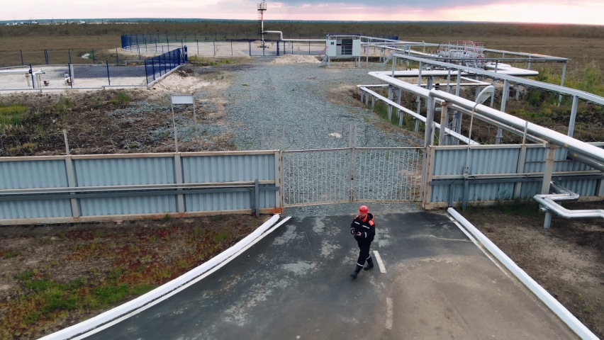 On the territory of the industrial complex for the production and transportation of oil and gas, workers in overalls and a helmet are carried out. An oil refining complex deep in the permafrost swamps Royalty-Free Stock Footage #1078620050