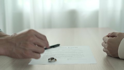 love problem and divorce. Husband and wife remove married ring between waiting sign divorce document. Husband and wife quarrel problem family.