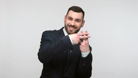 Young adult man in black suit making hashtag gesture looking at camera with toothy smile, tagging popular internet content, hash sign with viral message. Indoor studio shot isolated on gray background