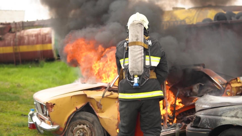On the Car Crash Traffic Accident Scene: A fire rescue worker professionally extinguishes a fire in a car with a fire extinguisher. A lot of fire and smoke. Unblocking of victims. First aid services Royalty-Free Stock Footage #1078630904