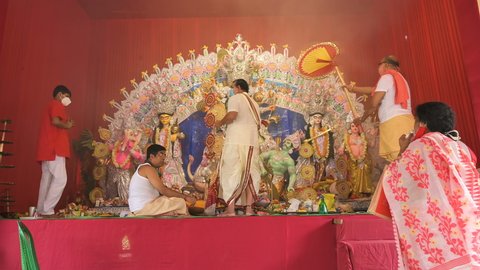 Howrah, West Bengal, India - 25th October 2020 : Goddess Durga is being worshipped by masked Hindu priest with holy panchapradip during sondhipujo aarti with holy smoke. Shonkho is played. Wide angle.