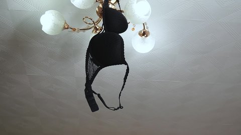 Black women's bra hanging on a chandelier in an apartment, tilting up