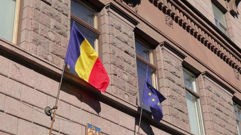 Romania flag and European Union flag hang side by side on the building wall