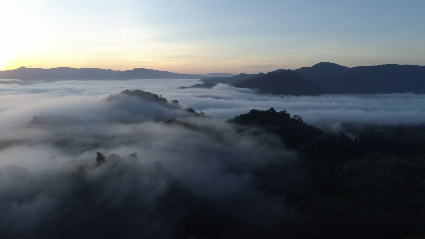 Amazing sea of fog move flowing over mountain Sunrise or sunset sky fog scenic aerial view.Drone flies over sky Rainforest. clouds and fog in sunrise at golden sun.Nature background concept