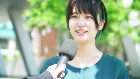 Young asian woman taking interview on the street.