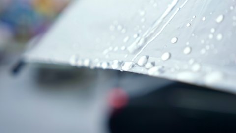 close-up of raindrops flowing down from a transparent umbrella.