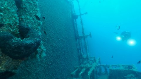 Scuba diver photographer swims on the shipwreck Swedish ferry MS Zenobia, a flock of Mediterranean chromis fish swims around. Wreck diving. Mediterranean sea, Cyprus