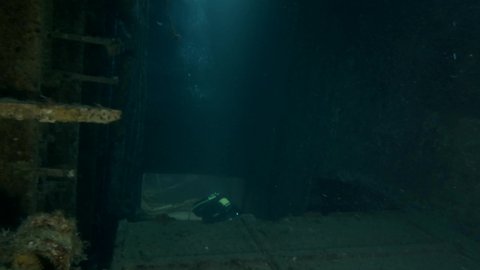 Scuba diver swims inside of the shipwreck Swedish ferry MS Zenobia. Wreck diving. Mediterranean sea, Cyprus