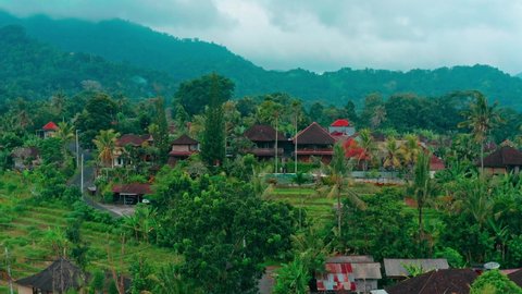 aerial top view on traditional balinese architecture with traveler man enjoying summer vacation at swimming pool on Villa in Ubud. 4K Aerial UHD video clip