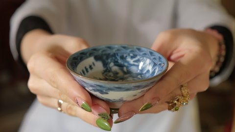 A tea master pours magical chinese tea into bowls in an authentic chinese ceremony. Authentic tea paraphernalia. Slow motion. Translation: good thoughts lead to a good life.
