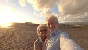 Portrait of couple of mature and old people enjoying summer at the beach looking to the camera taking a selfie together with the sunset at the background. Two active seniors traveling outdoors.
 - Powered by Shutterstock - Get 15% off with code: PIKWIZARD15