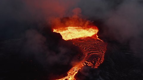 Slide and pan shot of molten lava flowing from volcano crater. Wildly boiling magma splashing into height. Fagradalsfjall volcano. Iceland, 2021