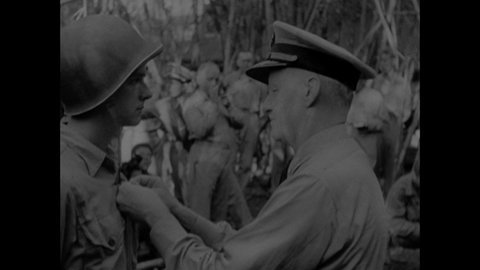 1940s: Animated map of Philippines, arrows crash down on islands, pan to Japan. Chester Nimitz, soldiers standing by tent. Nimitz pinning medal to soldier. Pan of soldiers. Hose spraying chain.