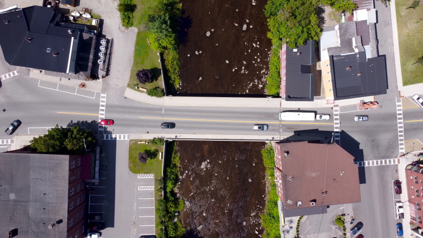 A 4k top-down drone video of Cars passing over the Connecticut River via a bridge in Lancaster New Hampshire.