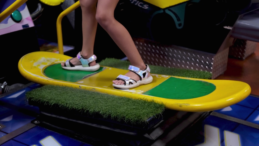 Child play a game machine. Creativity Game Concept. A little girl is riding a virtual snowboard. Weekends .
