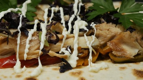 the chef is dressing the ingredients in the shawarma with white sauce. Lavash, a mixture of three fried peppers, chicken fillet and fresh herbs. Fast food concept.