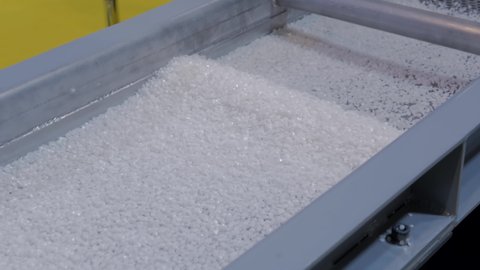 White recycled plastic granules - propylene or polyethylene pellets on shale shaker of waste plastic recycling machine. Separation, environmental protection, automated technology concept