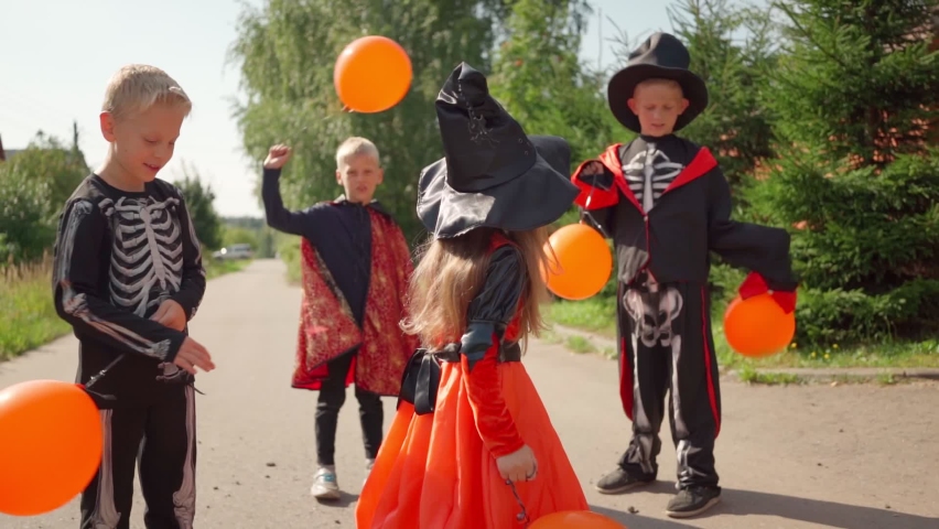 Halloween kids jump and fun with orange balloons. going collect candy. Trick-or-treating. Guising. Jack-o-lantern. Children in carnival costumes outdoors. Witch and skeletons. celebrate halloween | Shutterstock HD Video #1078689353