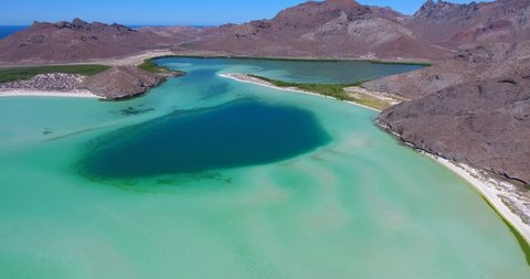 Slow Forward Aerial of Scenic Blue Hole, Long White Sand Beaches, Green Foliage and Desert Mountains in Background