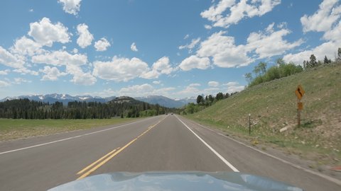 POV Driving a car on asphalt road in Montana mountains towards Yellowstone National Park. Blue sky on sunny day