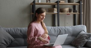 Pregnant woman sit on sofa strokes her belly use laptop talk to family on videoconference, get remote consultation via video call. Obstetrician gynaecologist give medical care, on-line counsel concept