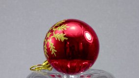 Red Christmas ball with a pattern rotates on a relief surface