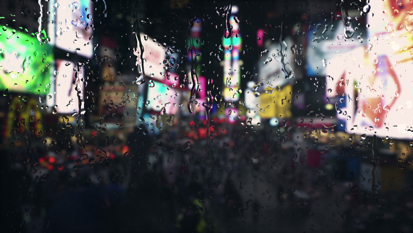 Rainfall in Time Square New York view from the window. Rain drops falling with bokeh lights of city at night. Raining in the city traffic. 4k