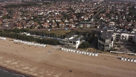 Sailing Dinghies in boat yard behind beach huts in Goring by Sea seafront in West Sussex. Aerial footage.