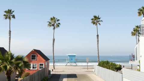 Colorful waterfront cottages, Oceanside California USA. Multicolor bungalow huts, summer sea, beachfront lodging. Many vacation houses on beach, ocean waves and palm trees. Lifeguard tower, watchtower