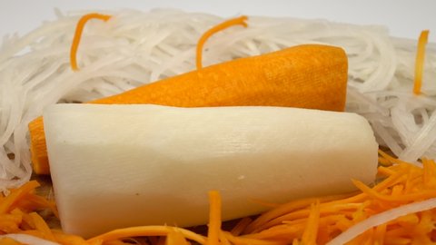 Peeled carrots and daikon radishes lie on a cutting board next to grated carrots and radishes. Carrot, daikon radishes, popular ingredients in vegetable salads and snacks