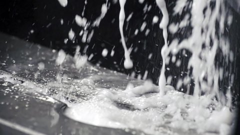 Water splashes with foam fall down From Turning Milling Machine at Modern Metal Factory. Industrial Water Drops With Foam at Production Line. Modern manufacturing plant. Close Up, Slow Motion