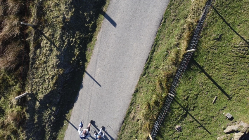 Close up aerial view of a father and son walking along a narrow road