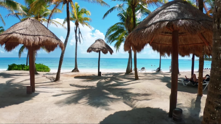 Gorgeous shot walking through a tropical beach with white sand, palm trees, and turquoise water on the beautiful Playa del Carmen in Riviera Maya, Mexico near Cancun on a sunny summer day on vacation. Royalty-Free Stock Footage #1078714370