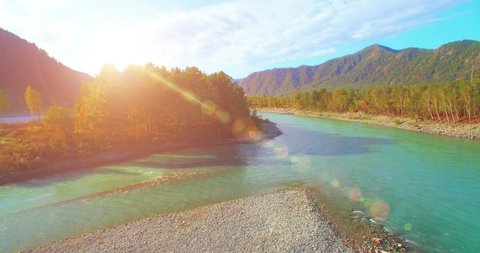 4k (UHD) aerial view. Low flight over fresh cold mountain river at cloudy summer morning. Green trees and sun rays on horisont. Fast horizontal movement