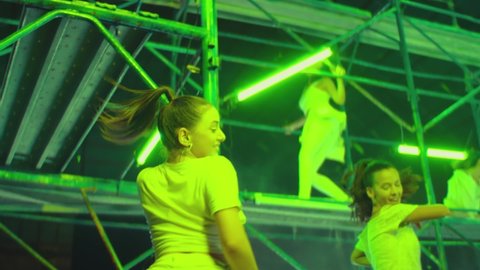 Many female dancers dressed in white shorts dancing inside abandoned building in high multistage  construction . Stylish Girls dancing, twerking , doing gymnastic movements , jumping . Slow motion 