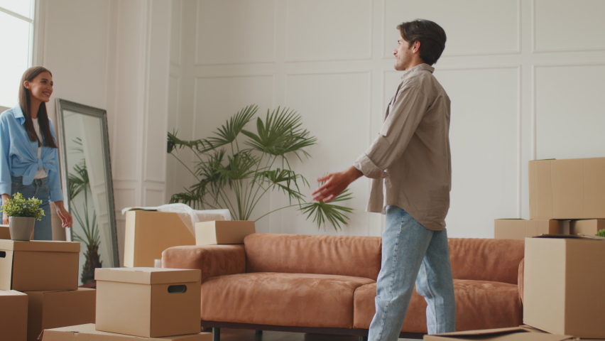 Home owners. Happy man hugging and lifting wife, laughing together, celebrating moving day in their new apartment, feeling excited moving into own house, slow motion Royalty-Free Stock Footage #1078721819