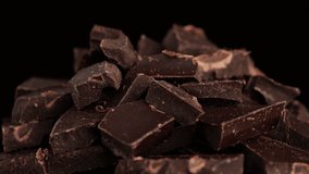 Chocolate. Chunks of dark chocolate on dark background, rotate. Gourmet dessert ingredient. Confectionery, confection concept. 4K UHD video