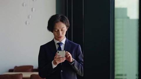 Asian businessman using a smart phone. Mobile app. Slow motion.