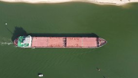 Big red dry cargo ship floats on water along the coast aerial drone top view. 4K video.
