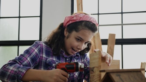 Active girl working with wood to build objects or furniture. Training activities as carpenter. Happy Student practice woodworking at homeschool. Professional skills to enhance children skill