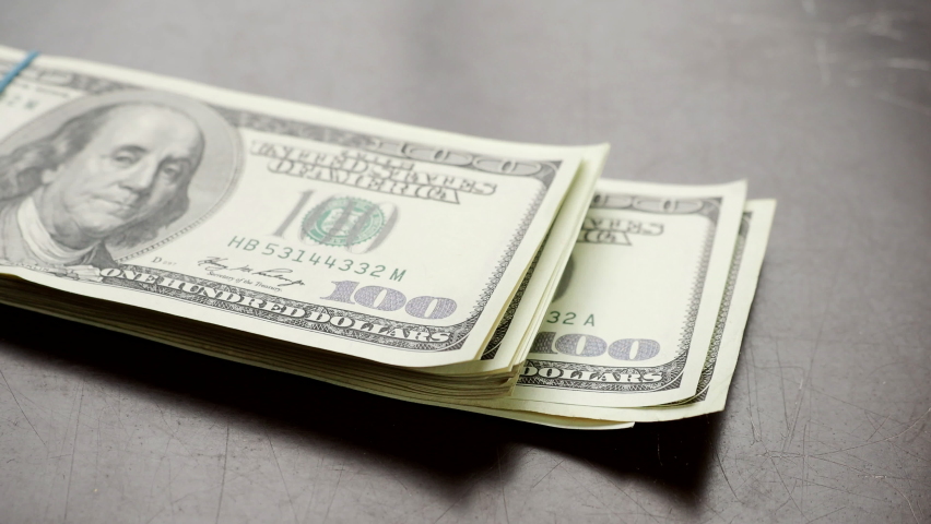 Hand counting pile of one hundred US banknotes over wooden table  in 4K VIDEO. Cash of hundred dollar bills, paper money currency.